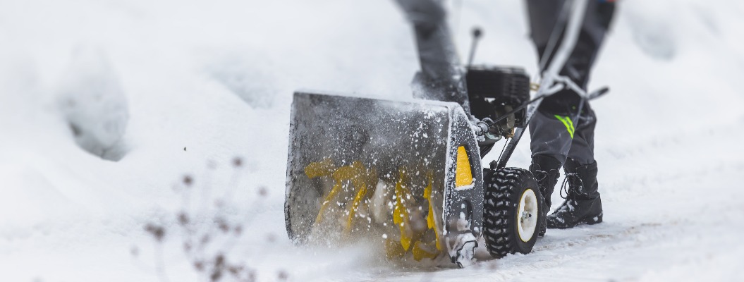 Prozess der Schneeräumung mit einer tragbaren Schneefräse, Arbeiter in Arbeitskleidung mit einer Gasschneefräse auf der Straße im Winter